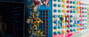 Colorful pop-up event backdrop with floral decorations, blue door, and vibrant circular patterns, reflecting creative corporate event design by Geo Events.